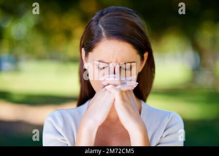 Un mal de tête frappe. une jeune femme attrayante qui a l'air stressée en plein air. Banque D'Images
