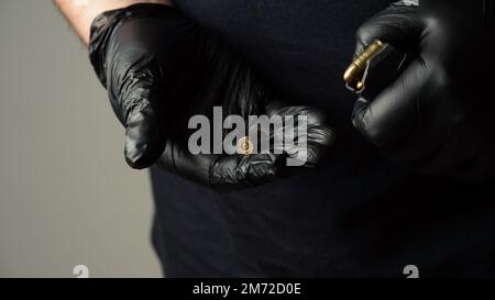 Un homme dans un T-shirt noir décharge le porte-pistolet avec 9 19 cartouches. La main de l'homme contient 9 19mm cartouches de pistolet Banque D'Images