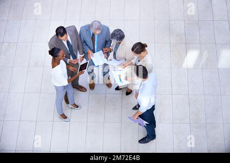 Analyse d'une équipe. un groupe de gens d'affaires divers se tenant et discutant de la paperasse. Banque D'Images