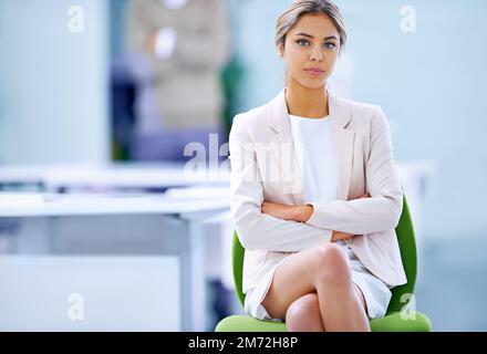 Shes s'est engagée dans sa carrière. Portrait d'une jeune femme d'affaires confiante assise sur sa chaise de bureau. Banque D'Images