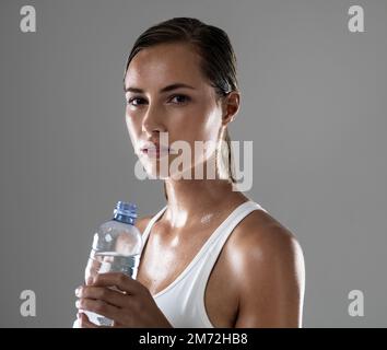 Nous avons dû nous hydrater. une jeune femme attirante prenant une pause de son entraînement pour boire un peu d'eau. Banque D'Images