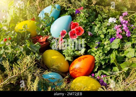 De grands oeufs en bois multicolores se trouvent sur un lit de fleurs, vue d'en haut Banque D'Images