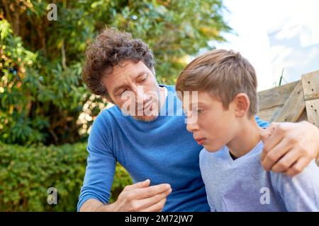 Il papas son gars. un père et un fils ayant un coeur à coeur dans l'arrière-cour. Banque D'Images