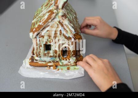 Enfants avec maison de pain d'épice, Une fille adolescente est en train de manger une maison de pain d'épice Banque D'Images