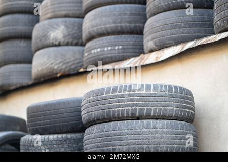 Vieux pneus en caoutchouc usés empilés avec des piles élevées. Déchets dangereux nécessitant un recyclage et une mise au rebut. Banque D'Images