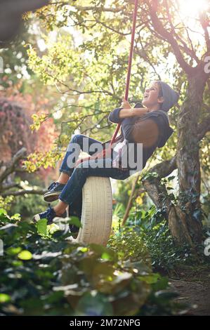 N'oubliez pas de jouer. Un préadolescent balançant sur une balançoire de pneu dans le jardin. Banque D'Images