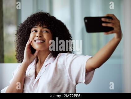 Selfie, beauté et soin de la peau avec une femme noire prenant une photo dans la salle de bains de sa maison le matin. Visage, téléphone et influenceur avec un Banque D'Images