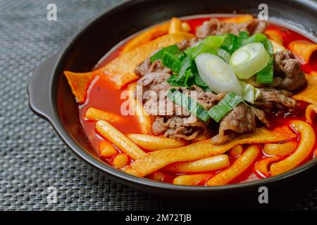 Tteokbokki, gâteau au riz frits par le fer : barre de gâteau au riz en tranches (garaetteok) ou fines bâtonnets de gâteau au riz (Tteokbokkkitteok) sautés dans une sauce piquante au gochujang Banque D'Images