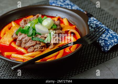 Tteokbokki, gâteau au riz frits par le fer : barre de gâteau au riz en tranches (garaetteok) ou fines bâtonnets de gâteau au riz (Tteokbokkkitteok) sautés dans une sauce piquante au gochujang Banque D'Images