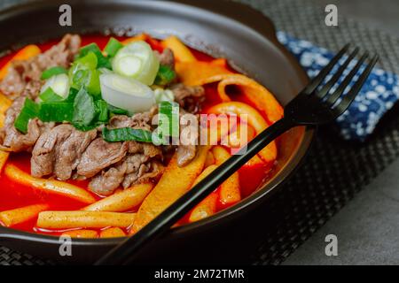 Tteokbokki, gâteau au riz frits par le fer : barre de gâteau au riz en tranches (garaetteok) ou fines bâtonnets de gâteau au riz (Tteokbokkkitteok) sautés dans une sauce piquante au gochujang Banque D'Images