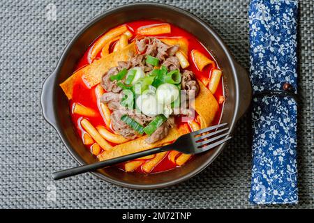 Tteokbokki, gâteau au riz frits par le fer : barre de gâteau au riz en tranches (garaetteok) ou fines bâtonnets de gâteau au riz (Tteokbokkkitteok) sautés dans une sauce piquante au gochujang Banque D'Images