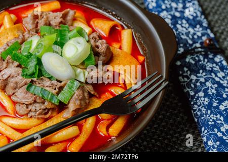 Tteokbokki, gâteau au riz frits par le fer : barre de gâteau au riz en tranches (garaetteok) ou fines bâtonnets de gâteau au riz (Tteokbokkkitteok) sautés dans une sauce piquante au gochujang Banque D'Images