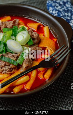 Tteokbokki, gâteau au riz frits par le fer : barre de gâteau au riz en tranches (garaetteok) ou fines bâtonnets de gâteau au riz (Tteokbokkkitteok) sautés dans une sauce piquante au gochujang Banque D'Images