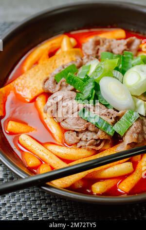 Tteokbokki, gâteau au riz frits par le fer : barre de gâteau au riz en tranches (garaetteok) ou fines bâtonnets de gâteau au riz (Tteokbokkkitteok) sautés dans une sauce piquante au gochujang Banque D'Images