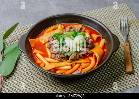 Tteokbokki, gâteau au riz frits par le fer : barre de gâteau au riz en tranches (garaetteok) ou fines bâtonnets de gâteau au riz (Tteokbokkkitteok) sautés dans une sauce piquante au gochujang Banque D'Images