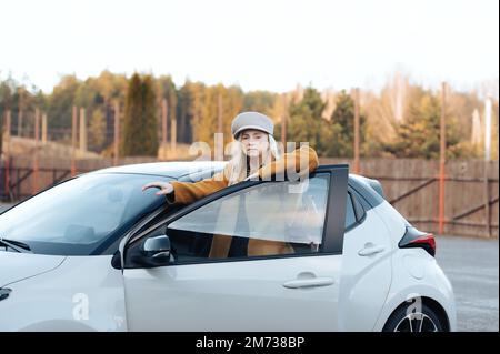 Femme d'affaires d'âge moyen élégante debout à la voiture, mode d'automne, portrait authentique Banque D'Images