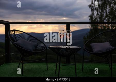 Champagne et cocktails sur table en verre, patio extérieur donnant sur les montagnes au coucher du soleil Banque D'Images