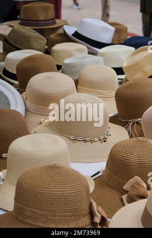 Bouquet de chapeaux de paille et de fedoras mis sur le stand le jour d'été sur le marché de rue Banque D'Images