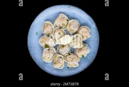 Boulettes russes pelmeni au beurre sur fond noir vue latérale Banque D'Images