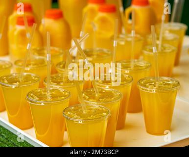 Plateau contenant des jus fraîchement pressés dans des tasses en plastique avec pailles Banque D'Images