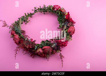 Couronne de fleurs artificielles colorées isolée sur fond rose Banque D'Images