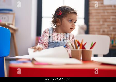 Adorable étudiante hispanique de fille assise sur table de dessin sur papier à la maternelle Banque D'Images