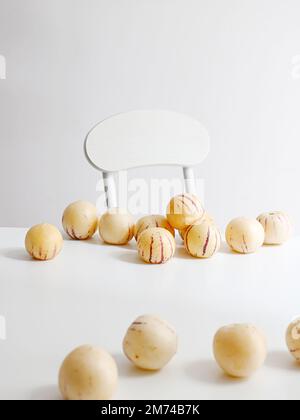 Un cliché vertical de melons de pepino frais sur une table blanche avec une chaise en arrière-plan Banque D'Images