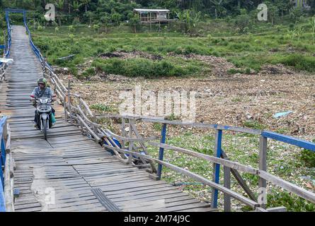 Régence de Bandung Ouest, Indonésie, 7 janvier 2023 - les résidents traversent un pont sous lequel il y a des tas de déchets sur les rives de la rivière Citarum. Banque D'Images