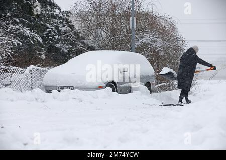 Météo saisonnière, fortes chutes de neige à Motala, en Suède, vendredi après-midi. Une femme pelle la neige d'une voiture enneigée. Banque D'Images