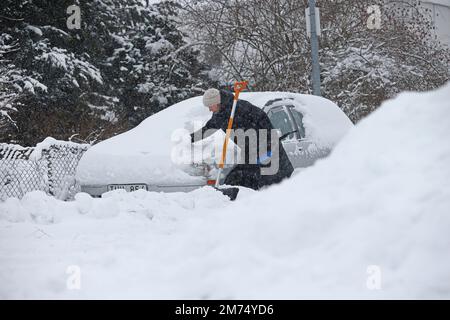 Météo saisonnière, fortes chutes de neige à Motala, en Suède, vendredi après-midi. Une femme pelle la neige d'une voiture enneigée. Banque D'Images