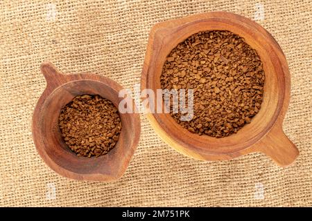 Café instantané parfumé dans deux tasses en bois sur un chiffon jute, macro, vue de dessus. Banque D'Images