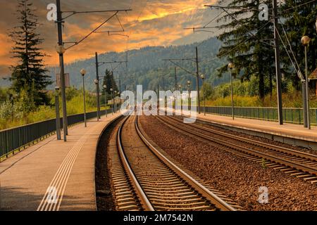 Un chemin de fer dans une zone montagneuse au coucher du soleil Banque D'Images