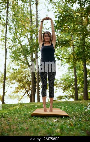 Une femme yogi pratique le yoga dans la forêt en automne. Elle est dans une posture de yoga de Crescent Moon. Banque D'Images