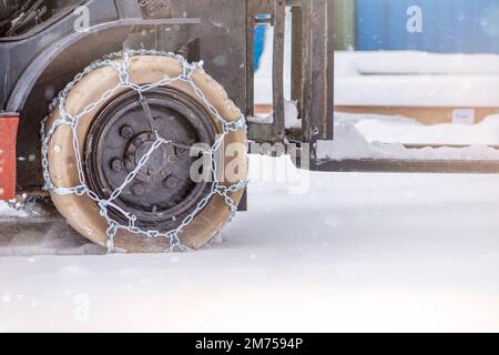 Chargeur de chargement en hiver sur neige. La chargeuse se porte sur la neige avec des chaînes sur les roues pour réduire le patinage et le patinage. Sécurité de conduite en hiver Banque D'Images