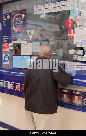 Ténérife, Espagne - 07 janvier 2023: Personne âgée méconnaissable devant un stand de loterie achetant des billets de loterie fréquentés par une femme Banque D'Images