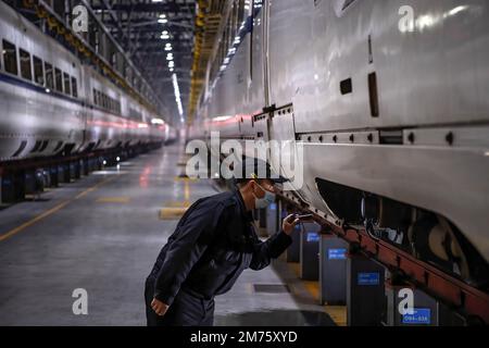 Wuhan, Hubei, Chine. 7th janvier 2023. Un technicien vérifie un train à grande vitesse CRH à la base de Wuhan. Environ 6,3 millions de voyages de passagers devraient être effectués en Chine samedi, le premier jour de la course de voyage du Festival de printemps de cette année, a déclaré l'opérateur ferroviaire national China State Railway Group. La Chine a récemment optimisé sa gestion de la lutte contre les épidémies et les mesures épidémiques pour les voyages ont également été optimisées le mois dernier. Les voyageurs n'ont plus besoin de résultats de tests négatifs sur les acides nucléiques ou de codes de santé, ne sont plus tenus de subir de tests d'acides nucléiques ou d'inspection sanitaire à leur arrivée Banque D'Images