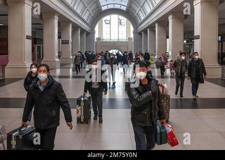 Wuhan, Hubei, Chine. 7th janvier 2023. Les passagers portant un masque facial transportent leurs bagages à la gare de Hankow le premier jour de la ruée vers le voyage du festival de printemps en Chine à Wuhan. Environ 6,3 millions de voyages de passagers devraient être effectués en Chine samedi, le premier jour de la course de voyage du Festival de printemps de cette année, a déclaré l'opérateur ferroviaire national China State Railway Group. La Chine a récemment optimisé sa gestion de la lutte contre les épidémies et les mesures épidémiques pour les voyages ont également été optimisées le mois dernier. Les voyageurs n'ont plus besoin de résultats négatifs de tests d'acides nucléiques ou de codes de santé, ne sont pas requis Banque D'Images