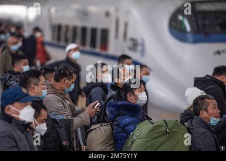 Wuhan, Hubei, Chine. 7th janvier 2023. Les pagers portant des masques faciaux embarquent à bord d'un train à la gare de Hankow le premier jour de la ruée vers le voyage du festival de printemps en Chine à Wuhan. Environ 6,3 millions de voyages de passagers devraient être effectués en Chine samedi, le premier jour de la course de voyage du Festival de printemps de cette année, a déclaré l'opérateur ferroviaire national China State Railway Group. La Chine a récemment optimisé sa gestion de la lutte contre les épidémies et les mesures épidémiques pour les voyages ont également été optimisées le mois dernier. Les voyageurs n'ont plus besoin de résultats négatifs de tests d'acide nucléique ou de codes de santé, ne sont pas tenus de se faire une demande de l'onu Banque D'Images