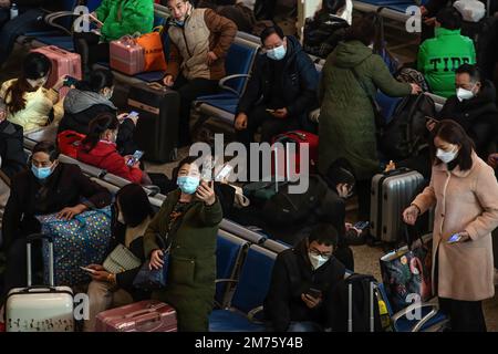 Wuhan, Hubei, Chine. 7th janvier 2023. Un passager portant un masque prend un selfie tout en attendant dans la zone de départ de la gare de Hankow le premier jour de la ruée vers le voyage du festival de printemps en Chine à Wuhan. Environ 6,3 millions de voyages de passagers devraient être effectués en Chine samedi, le premier jour de la course de voyage du Festival de printemps de cette année, a déclaré l'opérateur ferroviaire national China State Railway Group. La Chine a récemment optimisé sa gestion de la lutte contre les épidémies et les mesures épidémiques pour les voyages ont également été optimisées le mois dernier. Les voyageurs n'ont plus besoin de résultats négatifs pour les tests d'acide nucléique Banque D'Images