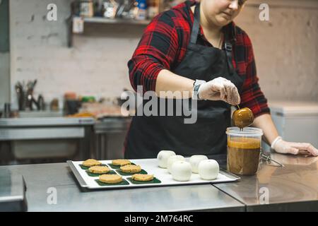 Faire de délicieuses friandises. Chef de boulangerie professionnel créant un nouveau dessert. Pommes couvertes de sauce caramel. Photo de haute qualité Banque D'Images