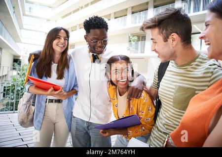 Un groupe d'étudiants joyeux rient sur le campus, laissant leurs cours Banque D'Images