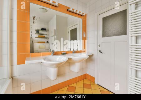 une salle de bains avec carrelage orange et blanc sur les murs, deux lavabos et un miroir dans le mur derrière lui Banque D'Images