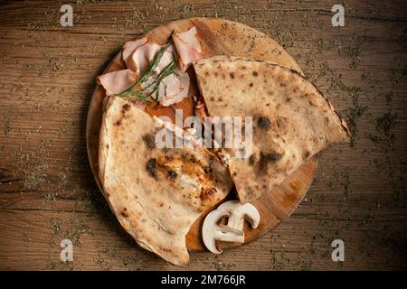 pizza au calzone en tranches sur une assiette en bois, vue sur le dessus. Banque D'Images