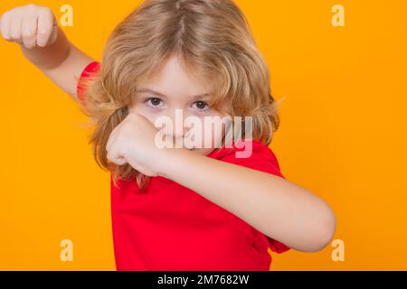 Enfant avec le combat gestuel poing. Andry enfant garçon en t-shirt rouge faisant un geste d'arrêt sur un arrière-plan isolé de studio. Protection des enfants, intimidation, abus et Banque D'Images