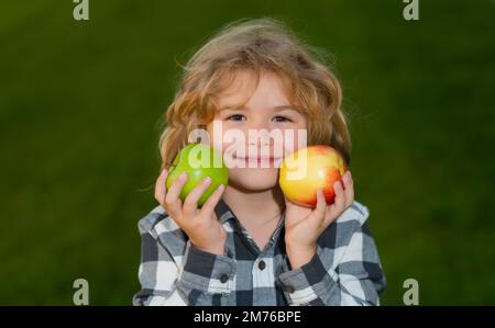 Pomme fraîche et mûre pour les enfants. Enfant habillé décontracté tenant et pomme avec un sourire et montrant mange des aliments sains. Banque D'Images