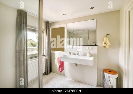 une salle de bains avec un lavabo et un miroir sur le mur à côté de la cabine de douche dans la photo est prise de l'extérieur Banque D'Images