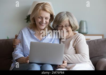 Joyeuse fille adulte heureuse et mère âgée se reposant sur un canapé Banque D'Images