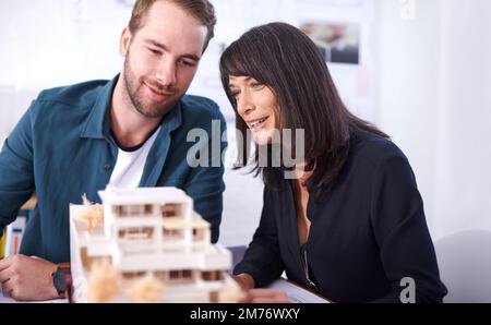 C'est vraiment unique. Deux architectes travaillant sur un modèle de maison. Banque D'Images