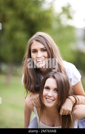 Charmant et animé, et profiter de la vie. une jeune femme qui donne à son ami une promenade en porcgyback dans le parc. Banque D'Images