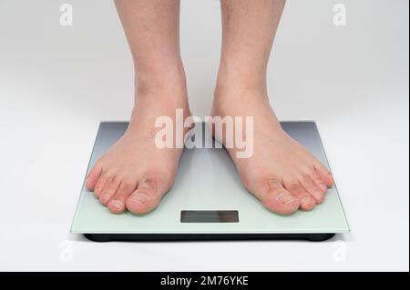 Pieds d'homme d'âge moyen asiatique mesurant le poids Banque D'Images